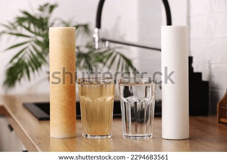 House water filtration system to drinkable condition. New clean water filter cartridge and glass of clear water. Used cartridge in rust and glass of dirty water on tabletop kitchen. World aqua day