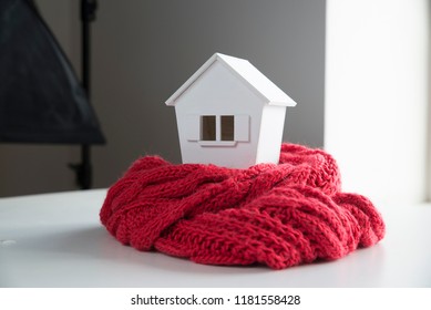 House In Winter - Heating System Concept And Cold Snowy Weather With Model Of A House Wearing A Knitted Cap