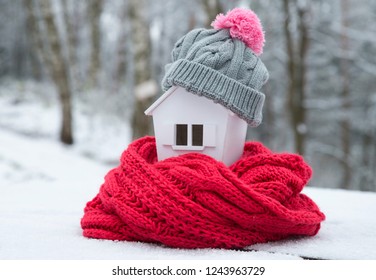 House In Winter - Heating System Concept And Cold Snowy Weather With Model Of A House Wearing A Knitted Cap