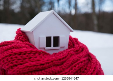 House In Winter - Heating System Concept And Cold Snowy Weather With Model Of A House Wearing A Knitted Cap