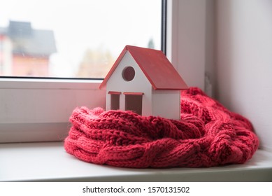 House In Winter - Heating System Concept And Cold Snowy Weather With Model Of A House Wearing A Knitted Cap