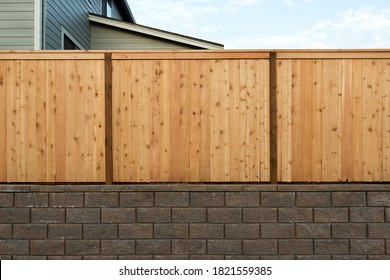 House Wood Fence Over Concrete Stone Retaining Wall In Suburban Neighborhood