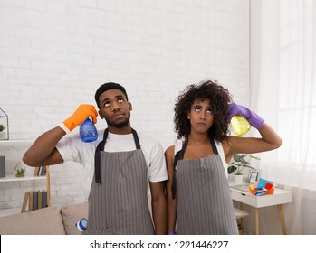 House works are killing. Young african-american couple holding spray detergents near heads like guns, copy space