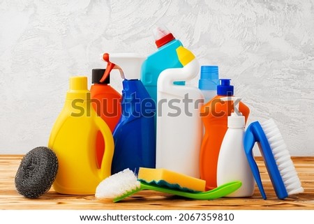 Household cleaning detergents on wooden table against gray background
