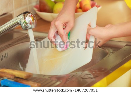 Household. Closeup woman doing the washing up in kitchen cleaning plastic cutting board