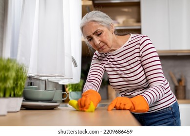 Household Duties. Tired Senior Woman Cleaning Table In Kitchen With Rag, Exhausted Elderly Lady Wearing Rubber Gloves Removing Dirt Stains From Surface, Making Domestic Chores, Closeup - Powered by Shutterstock