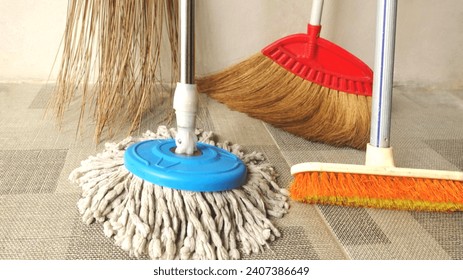 Household equipment for cleaning floors. Brushes, brooms and mops are on the tile floor. Concept of house cleaning.  - Powered by Shutterstock