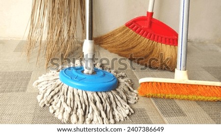 Household equipment for cleaning floors. Brushes, brooms and mops are on the tile floor. Concept of house cleaning. 