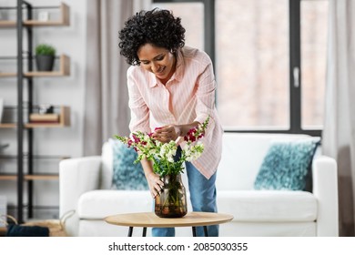 Household, Home Improvement And Interior Concept - Happy Smiling Young Woman Placing Flowers On Coffee Table