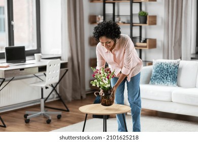 Household, Home Improvement And Interior Concept - Happy Smiling Young Woman Placing Flowers On Coffee Table
