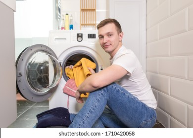 Household man sitting at home washing things in the washing machine - Shutterstock ID 1710420058