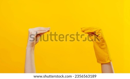 Household product advertising. Cleaning play. Socks show imitation. Woman hand meeting arm in protective gloves talking quarreling isolated on yellow background copy space.