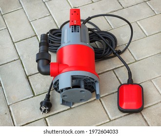 Household submersible pump with plastic housing lies on stone floor of courtyard