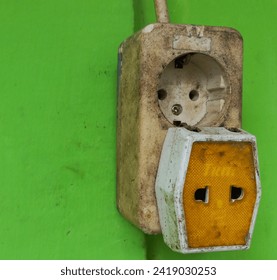 Household three-way socket plug. Multiple power socket with connected plugs. Isolated on green background.