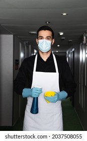 Housekeeper In Medical Mask And Rubber Gloves Holding Spray Bottle With Rag