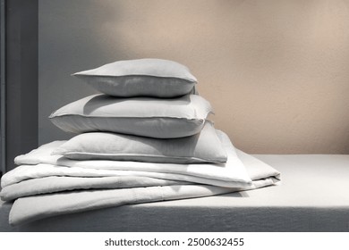 Housekeeping, laundry day concept. Clean bedding, memory foam pillows in french pillowcases and down blanket on mattress in bedroom. Textile on bed, blanket and cushions against copy space background