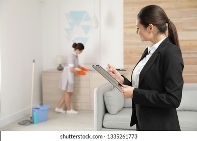 Housekeeping Manager Checking Maid Work In Hotel Room