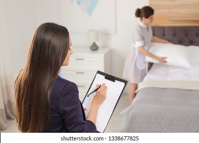 Housekeeping Manager Checking Maid Work In Hotel Room