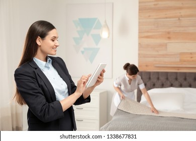 Housekeeping Manager Checking Maid Work In Hotel Room