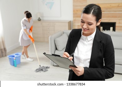 Housekeeping Manager Checking Maid Work In Hotel Room