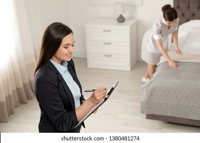 Housekeeping Manager Checking Maid Work In Hotel Room