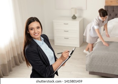 Housekeeping Manager Checking Maid Work In Hotel Room