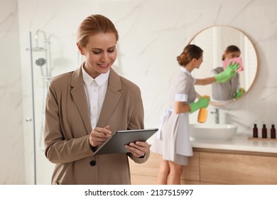 Housekeeping Manager With Tablet Checking Maid's Work In Hotel Bathroom