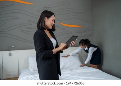 Housekeeping Manager Working On Digital Tablet And Controlling The Work Of Staff In The Hotel Room Before Guest's Arrival.