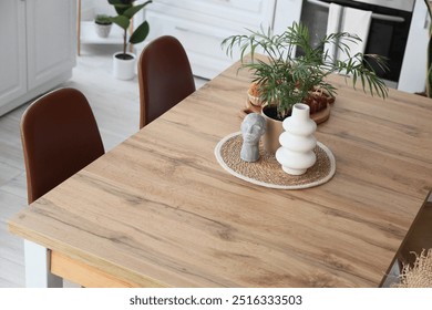 Houseplant, vase and statuette on wooden table in dining room - Powered by Shutterstock