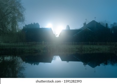 Houses Against Bright Street Lights. Reflected In Water. On A Moody, Misty, Winters Night. UK