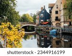 Houses and boats on the river Yare at Norwich city centre in Norfolk in autumn. Townhouses Buildings At Waterfront. Suburb Houses And Residential Building Near River In Europe. Selective focus.