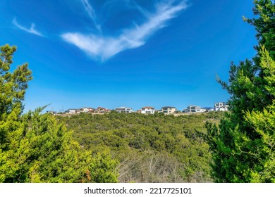 Houses At Comanche Canyon Ranch In Austin Texas Framed By Vibrant Green Leaves. Scenic Residential Neighborhood By The Lake Austin With Blue Sky View On A Sunny Day.