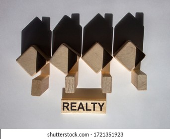 Houses created by shadows from wooden cubes. The word 'realty' on a wooden block.