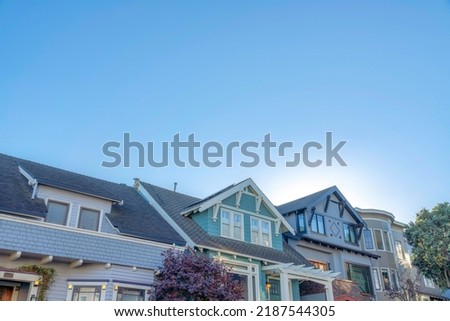 Houses with decorative dentils and brackets in San Francisco, California. There are two houses on the left with dormer roofs and painted wood sidings near the house on the right with curved walls.