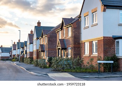 Houses in England with typical red bricks at sunset - Main street in a new estate with typical British houses on the side - Real estate and buildings concepts in UK - Powered by Shutterstock