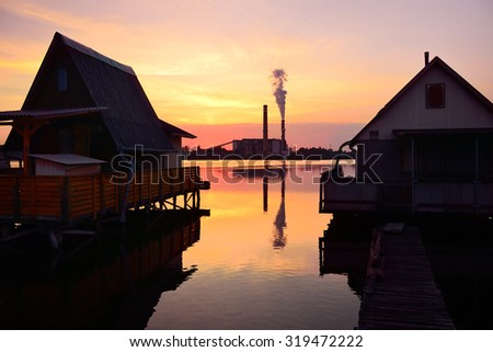 Houses on the water and old factory with lot of pollution during summer sunset	