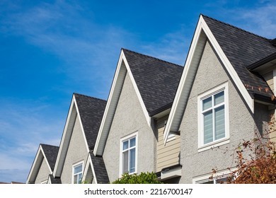 Houses with shingle roof against blue sky. Edge of roof shingles on top of the houses dark asphalt tiles on the roof. Nobody, street photo, selective focus - Shutterstock ID 2216700147