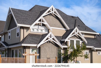 Houses with shingle roof against blue sky. Edge of roof shingles on top of the houses dark asphalt tiles on the roof. Nobody, street photo, selective focus - Shutterstock ID 2226794145