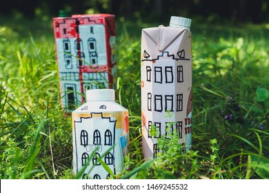 Houses And Toy Cars Made From Milk Bags On Grass. DIY Paper Milk Bag. Creative Paper Milk Bag Ideas. Recycle Crafts.