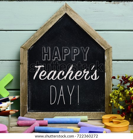 a house-shaped chalkboard with the text happy teachers day written in it on a rustic wooden table full of pieces of chalk of different colors