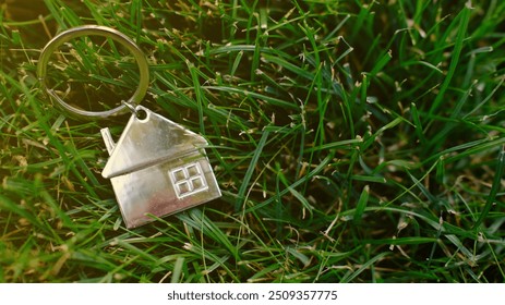 house-shaped keychain against green grass. Real estate, property ownership, new home concept. - Powered by Shutterstock