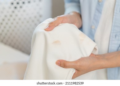 Housewife, asian young woman hand in holding shirt, showing making stain, spot dirty or smudge on clothes, dirt stains for cleaning before washing, making household working at home. Laundry and maid. - Shutterstock ID 2111982539