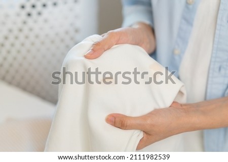 Housewife, asian young woman hand in holding shirt, showing making stain, spot dirty or smudge on clothes, dirt stains for cleaning before washing, making household working at home. Laundry and maid.