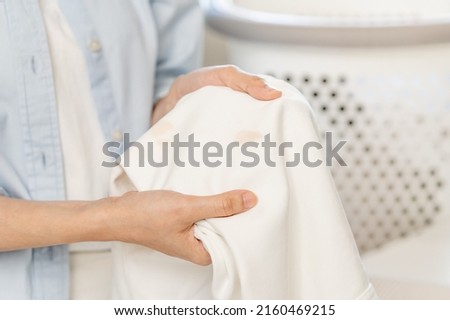 Housewife, asian young woman hand in holding shirt, showing making stain, spot dirty or smudge on clothes, dirt stains for cleaning before washing, making household working at home. Laundry and maid.