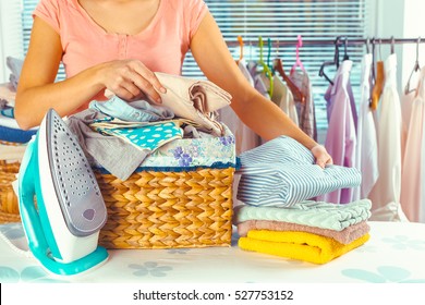 Housewife Bringing A Huge Pile Of Laundry On The Ironing Board