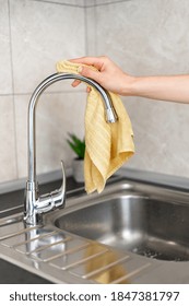 Housewife Cleaning Water Tap Over Metal Sink. Vertical Cropped View Of Woman Hand Holding Textile Cloth, Wipes Stainless Steel Faucet In The Kitchen