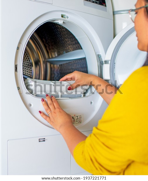 Housewife cleanup lints and dirt from tumble\
dryer filter. Clothes dryer lint filter that is covered with lint.\
Taking the lint out from dirty air filter of the dryer machine\
before use the\
machine.