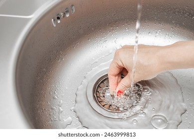 housewife closes the drain hole in the sink. sink drain plug. housewife fills the sink with water. stainless steel sink