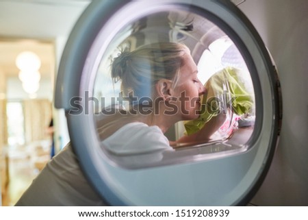 Housewife with fresh laundry in the washing machine or in the tumble dryer