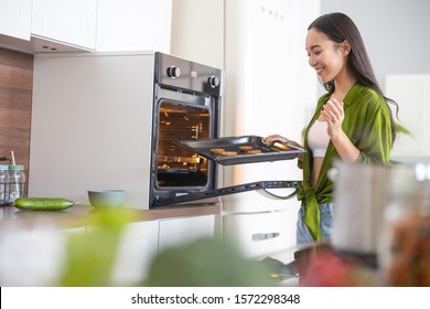 Housewife holding the baked cookies on a baking tray - Powered by Shutterstock